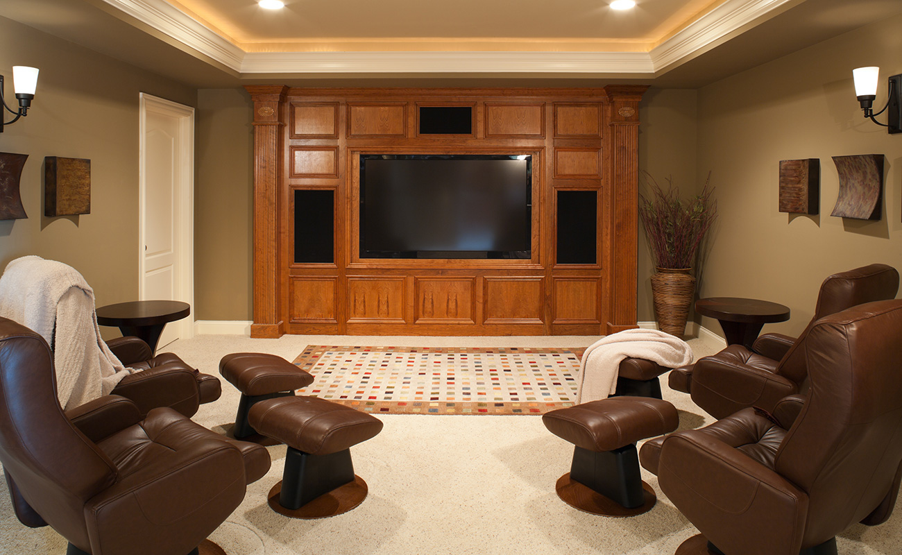 Home theatre with surround sound speakers and four brown leather sofas