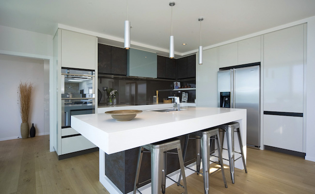 A kitchen with white splashback and cupboard