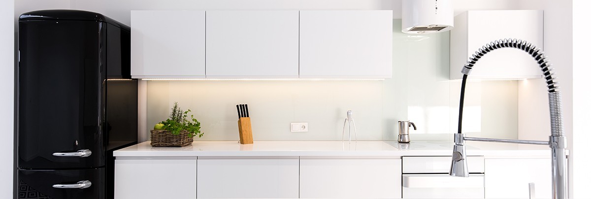 A kitchen with white splashback and cupboard