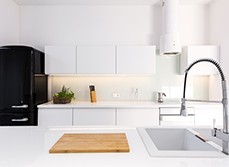 A kitchen with white splashback and cupboard