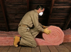 Man rolling out insulation in the roof of a home.