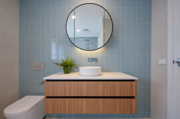 bathroom with light blue tiles and round mirror