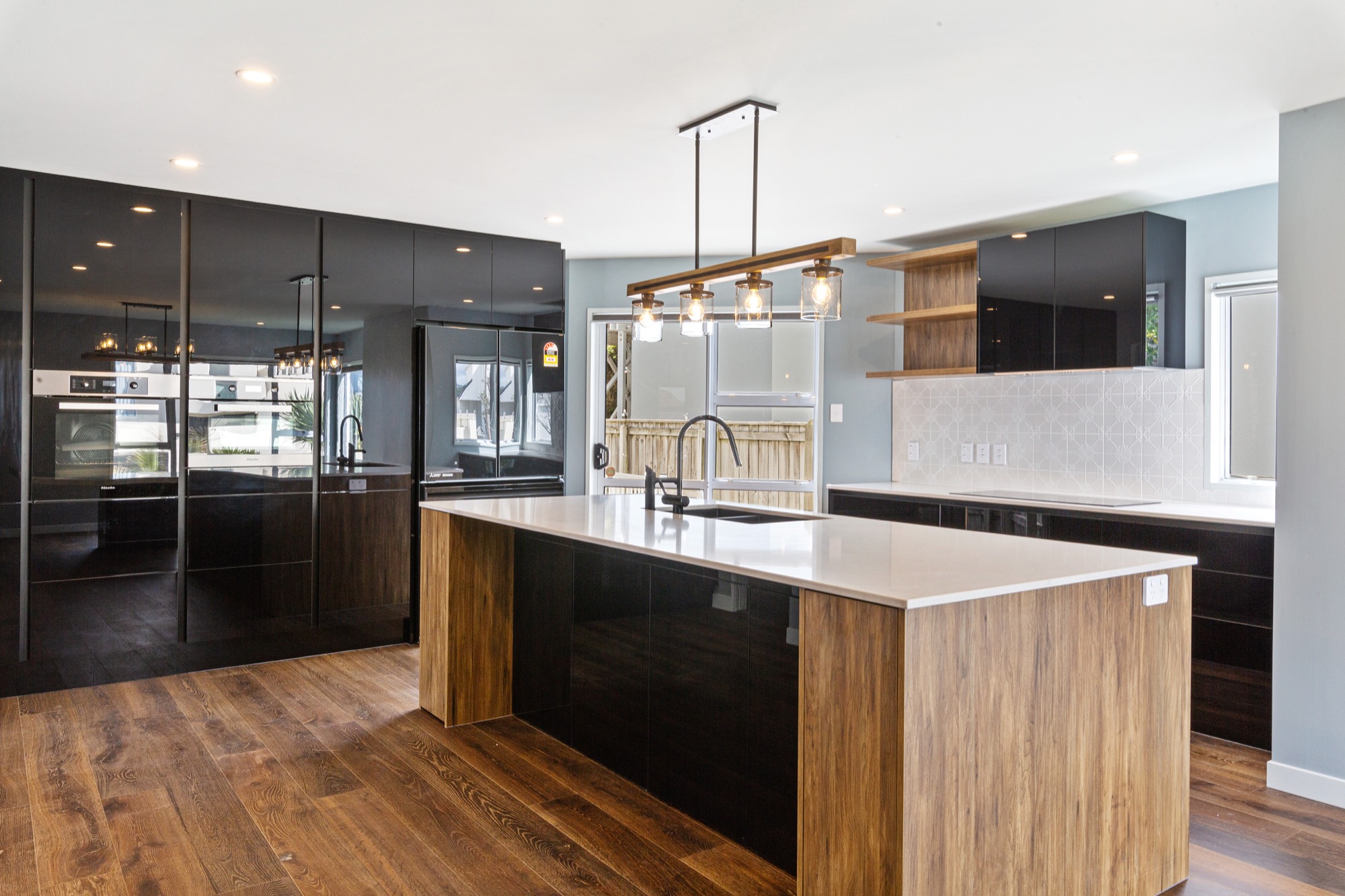 A black and timber style kitchen remodel in Woodlands TX. With a feature downlight across the white kitchen benchtop. 