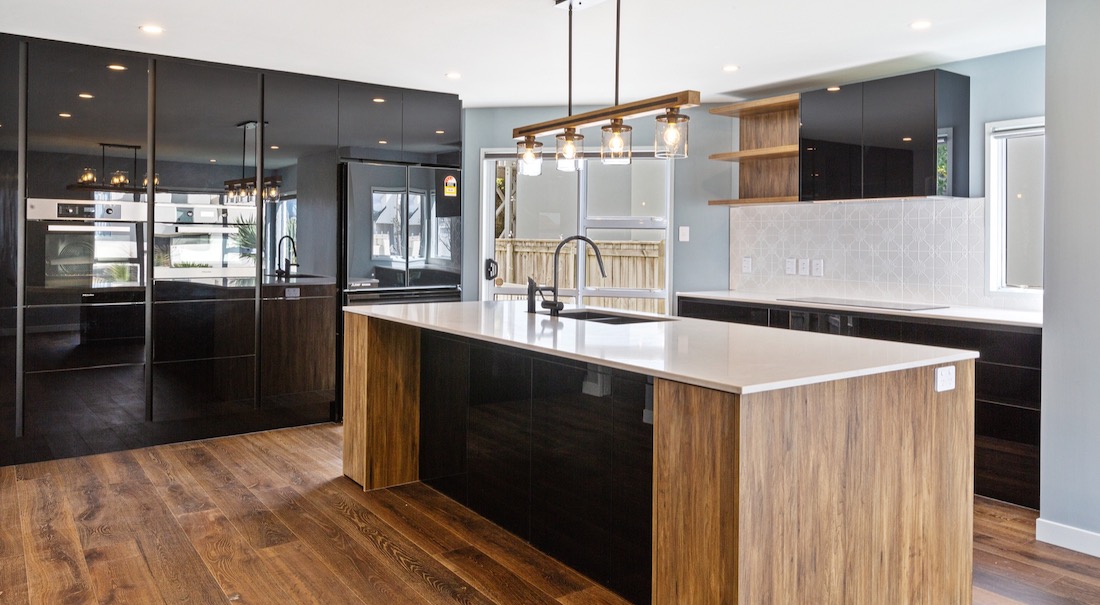 A sleek black and wooden finished kitchen remodel with a feature downlight and floor to ceiling storage.
