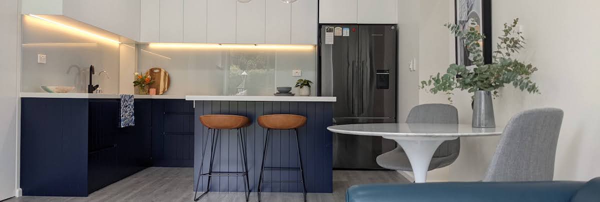small kitchen with blue features and a two chairs dining area