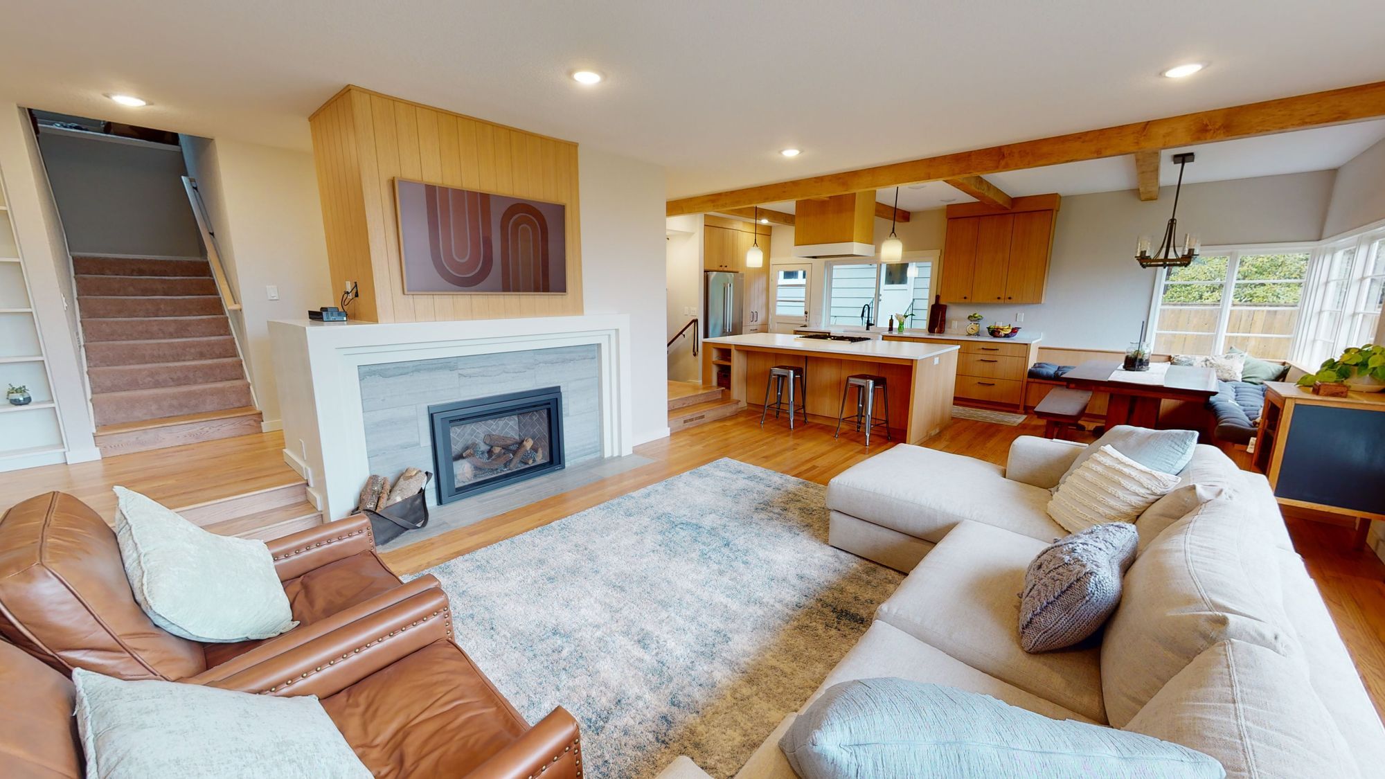 Open-concept living and dining area with modern kitchen, vaulted ceilings, and stylish pendant lighting from a full house remodel in Lake Oswego.